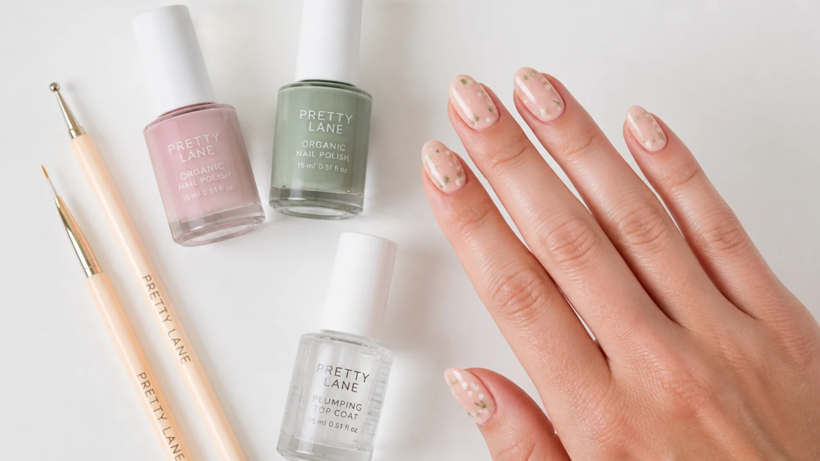 Flat lay of a dotting tool, striping brush, two summer polishes and a top coat on a white surface