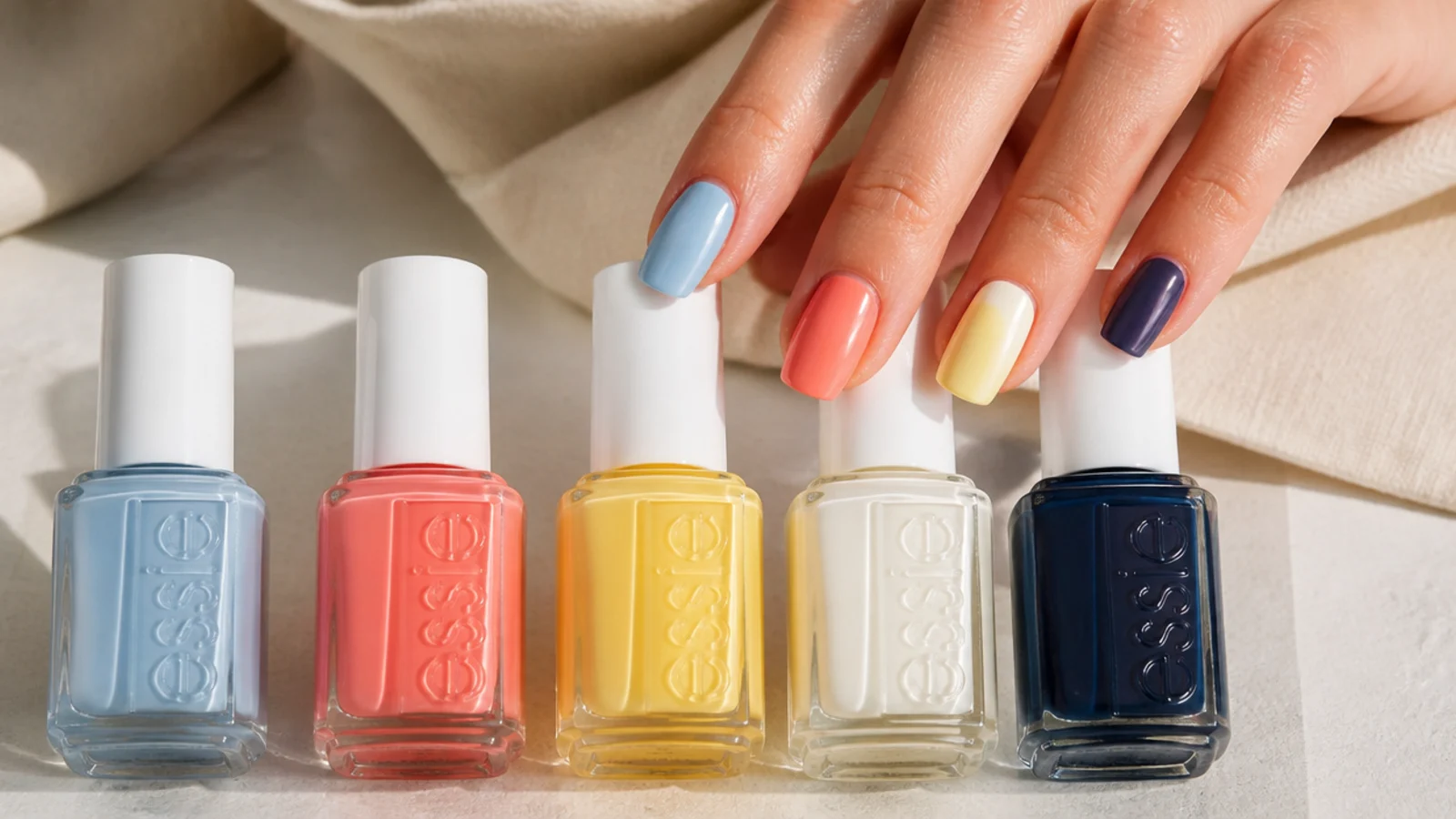 Row of summer polish bottles in sky blue coral butter yellow milky white and navy