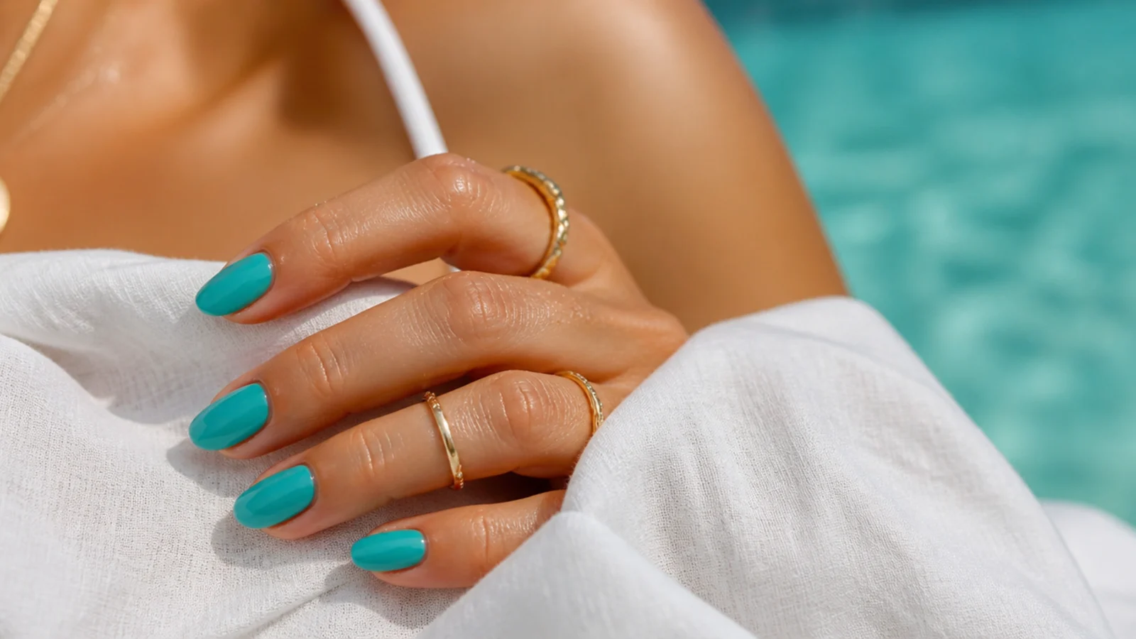 Bright turquoise nails on a tanned hand echoing an ocean blue-green shade