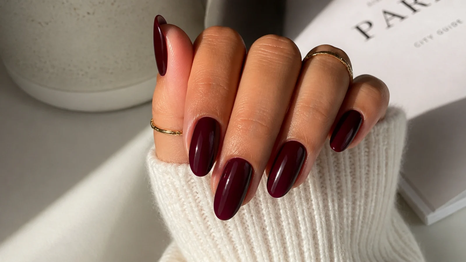Deep burgundy wine nails on a tanned hand with a glossy rich finish