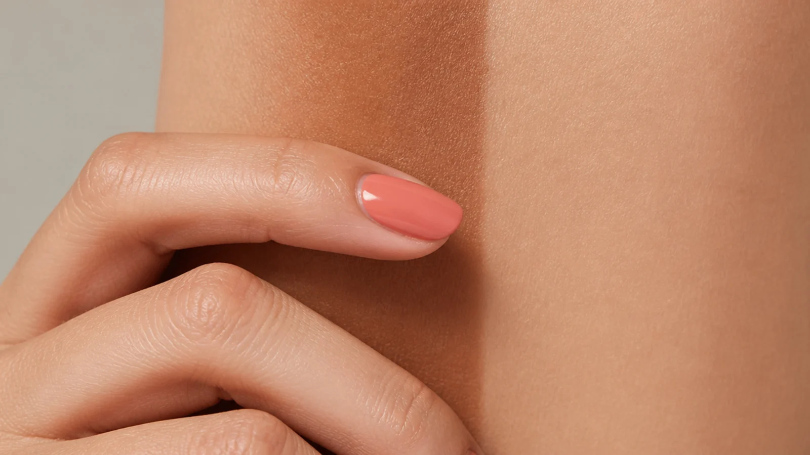 A single coral nail shown against a deep tan and a faded lighter tan side by side