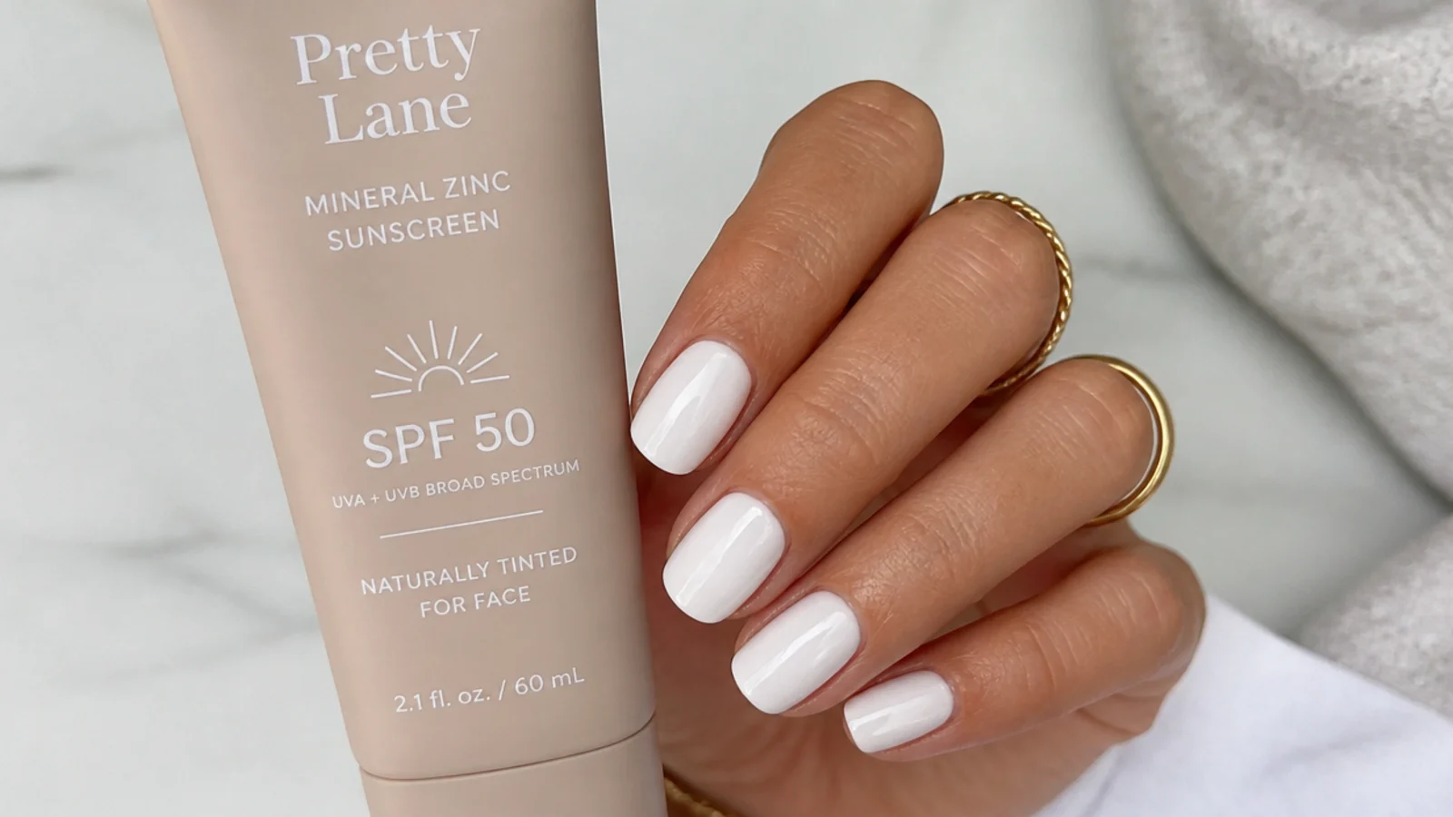 A tube of mineral zinc sunscreen beside a white nail with no yellow cast on the surface