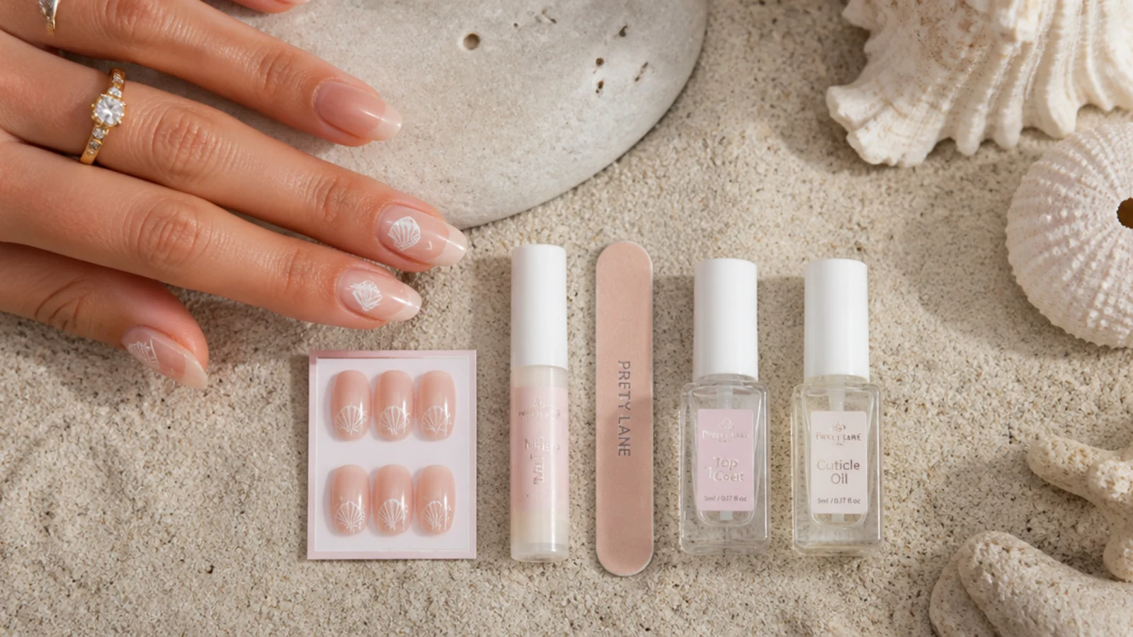 Flat lay of a five item beach nail repair kit with glue, mini file, topcoat, cuticle oil and spare press-ons