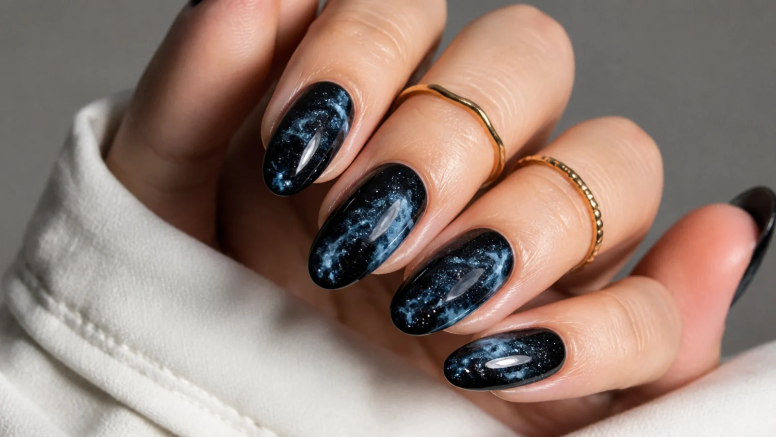 Deep black galaxy blooming gel nails with hints of blue and silver flecks