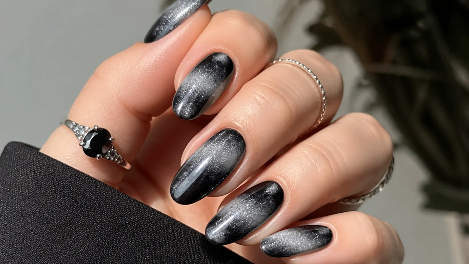 Black blooming gel nails finished with silver chrome shimmer over the haze