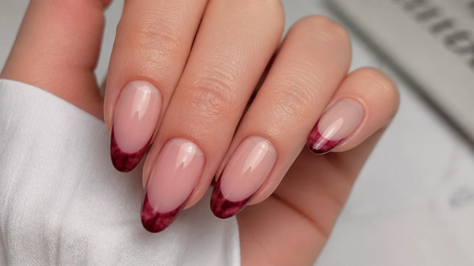 Nude blooming gel nails with a burgundy bloomed French tip