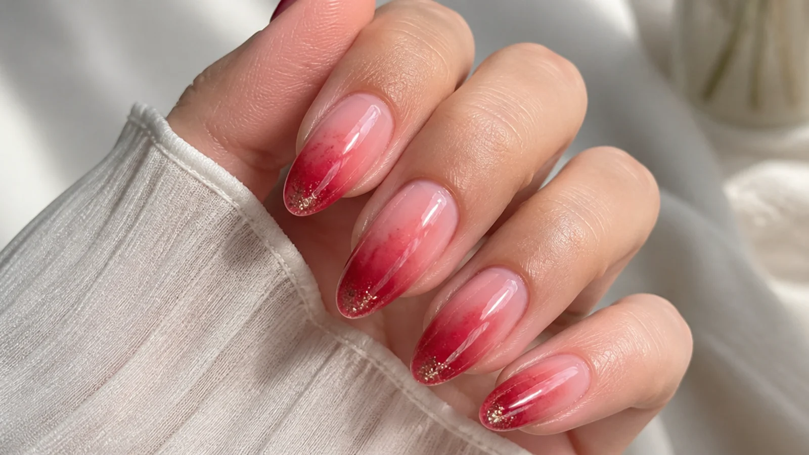Soft red blooming gel nails with fine glitter at the tips