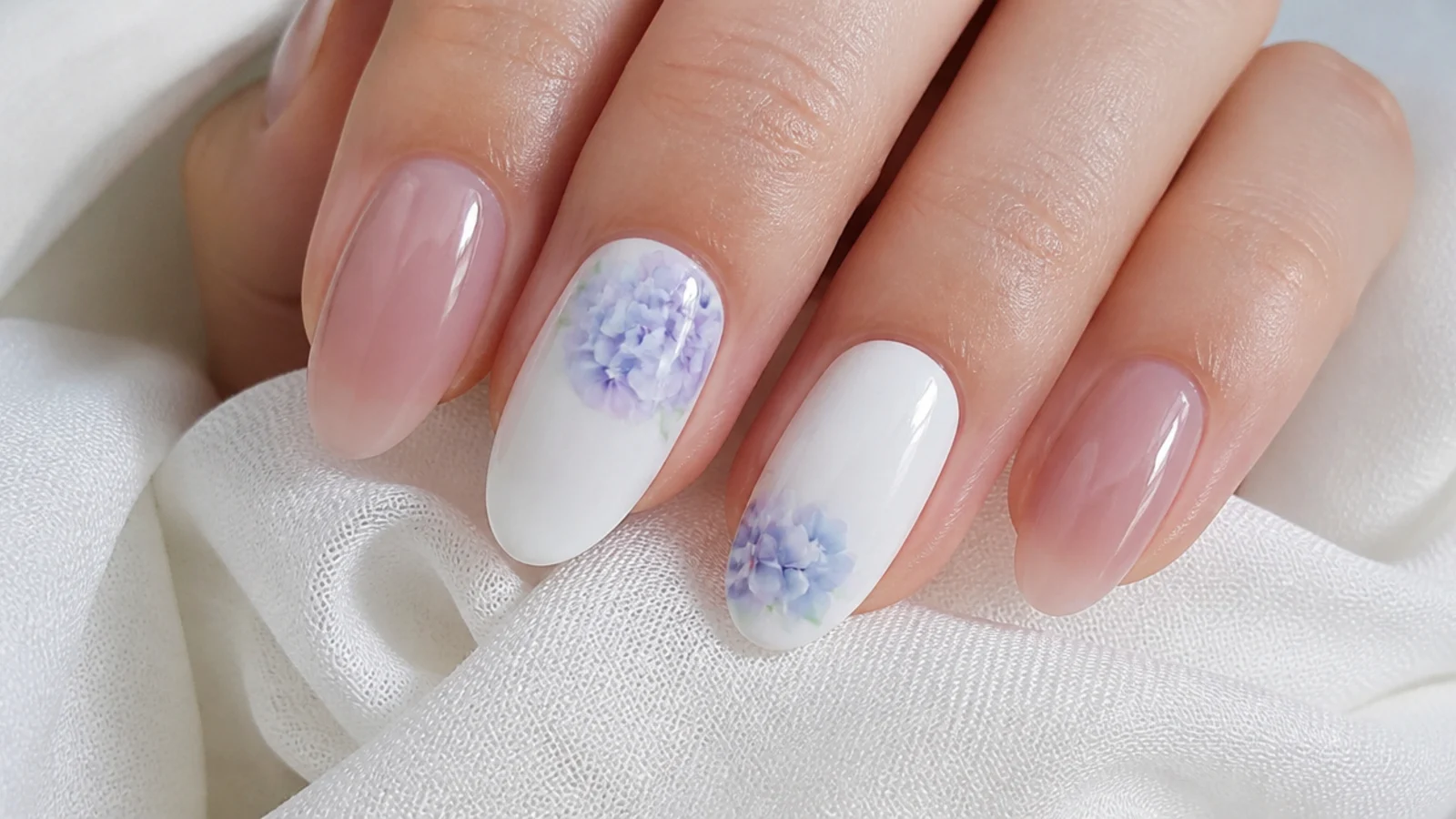 Cluster of tiny diffused pastel blue and purple hydrangea flowers on a white nail