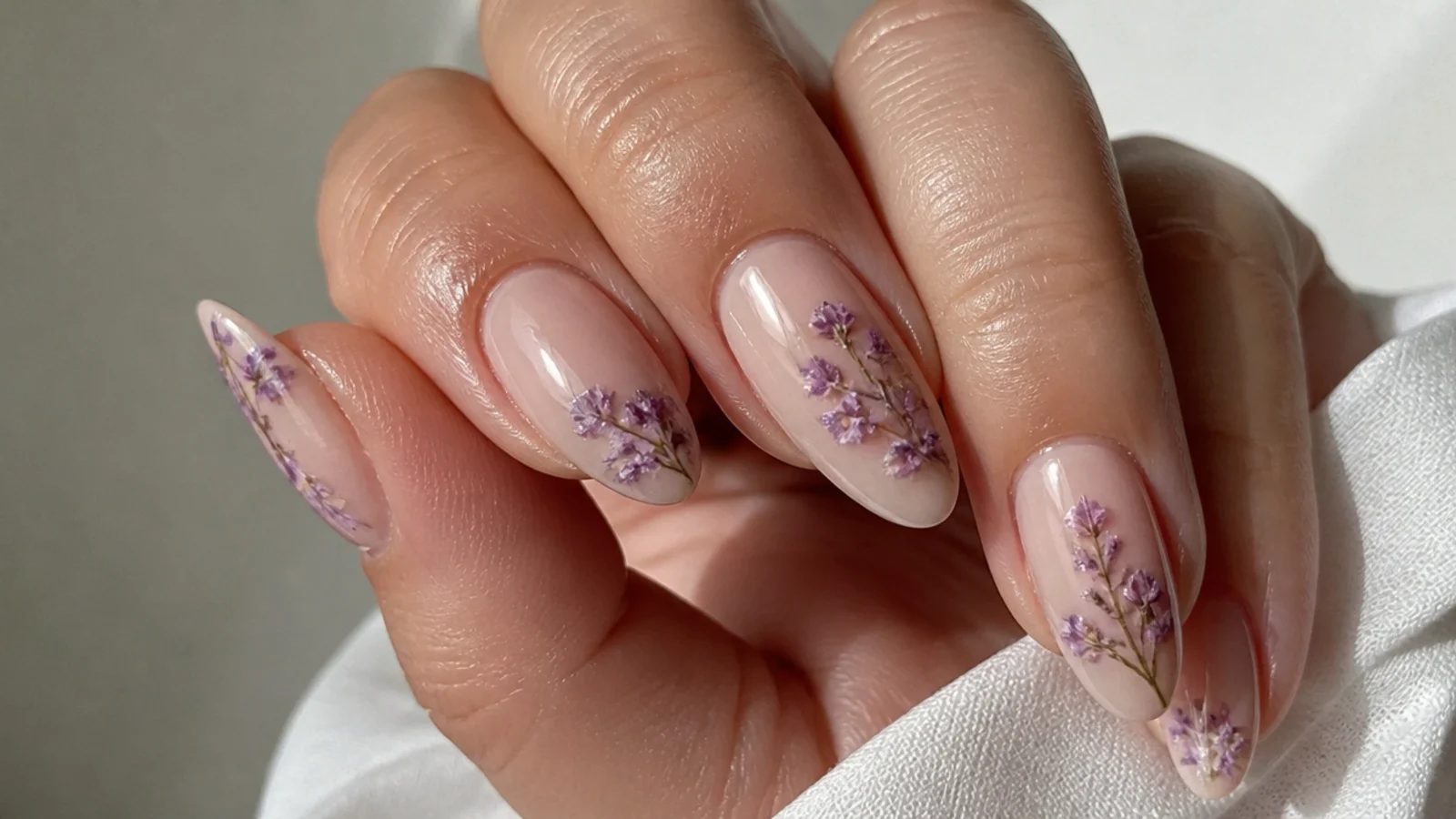 Lavender and purple wildflower sprigs diffused on nude blooming gel nails