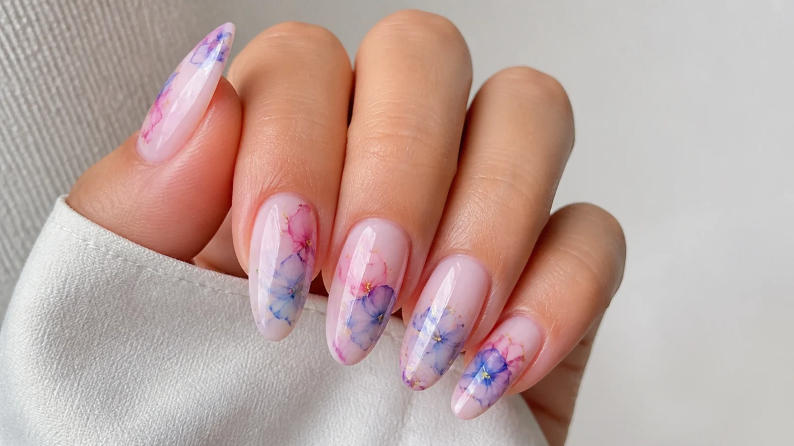 Soft watercolor blooming gel nails with diffused pink and blue florals