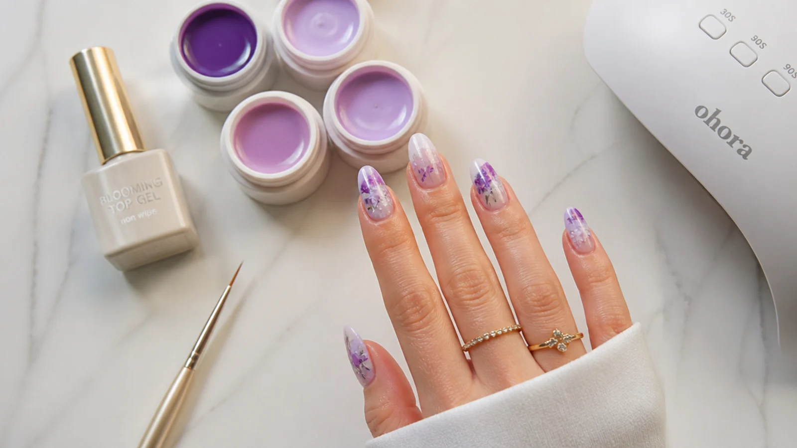 Flat lay of blooming gel, colored gels, lamp, liner brush and top coat