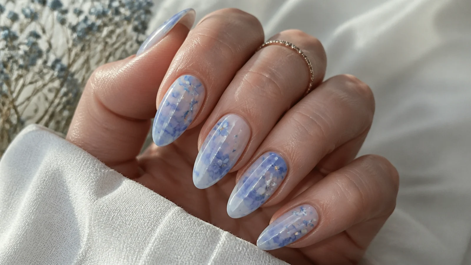 Soft blue blooming gel nails with a watercolor tie-dye fade on almond shapes