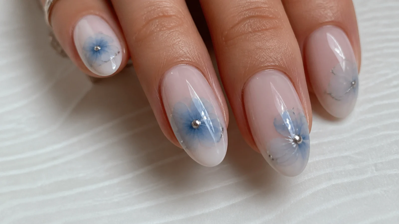 Close-up of blue gel color diffusing into a soft bloom on a nail