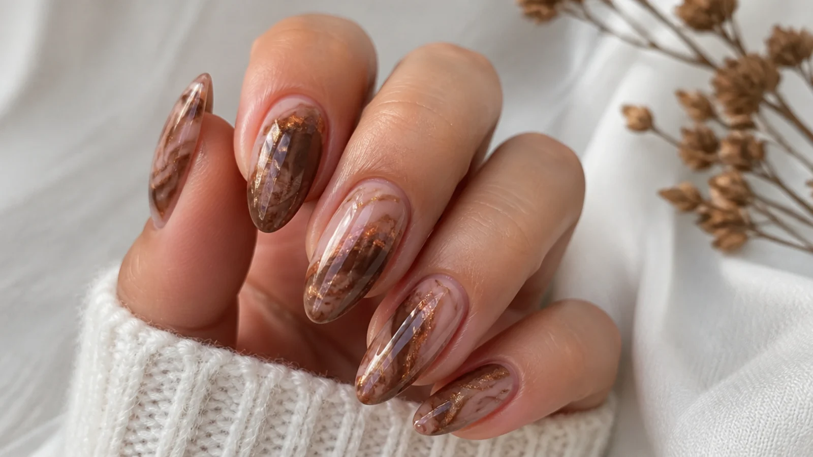 Brown blooming gel nails with a warm bronze chrome shimmer over the marble