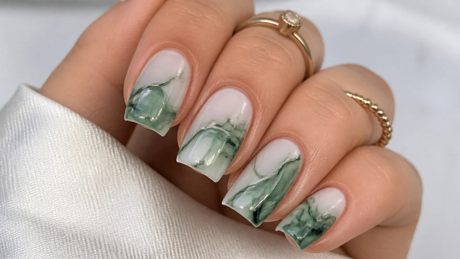 Emerald green ink marble pattern diffused over a white base on square nails