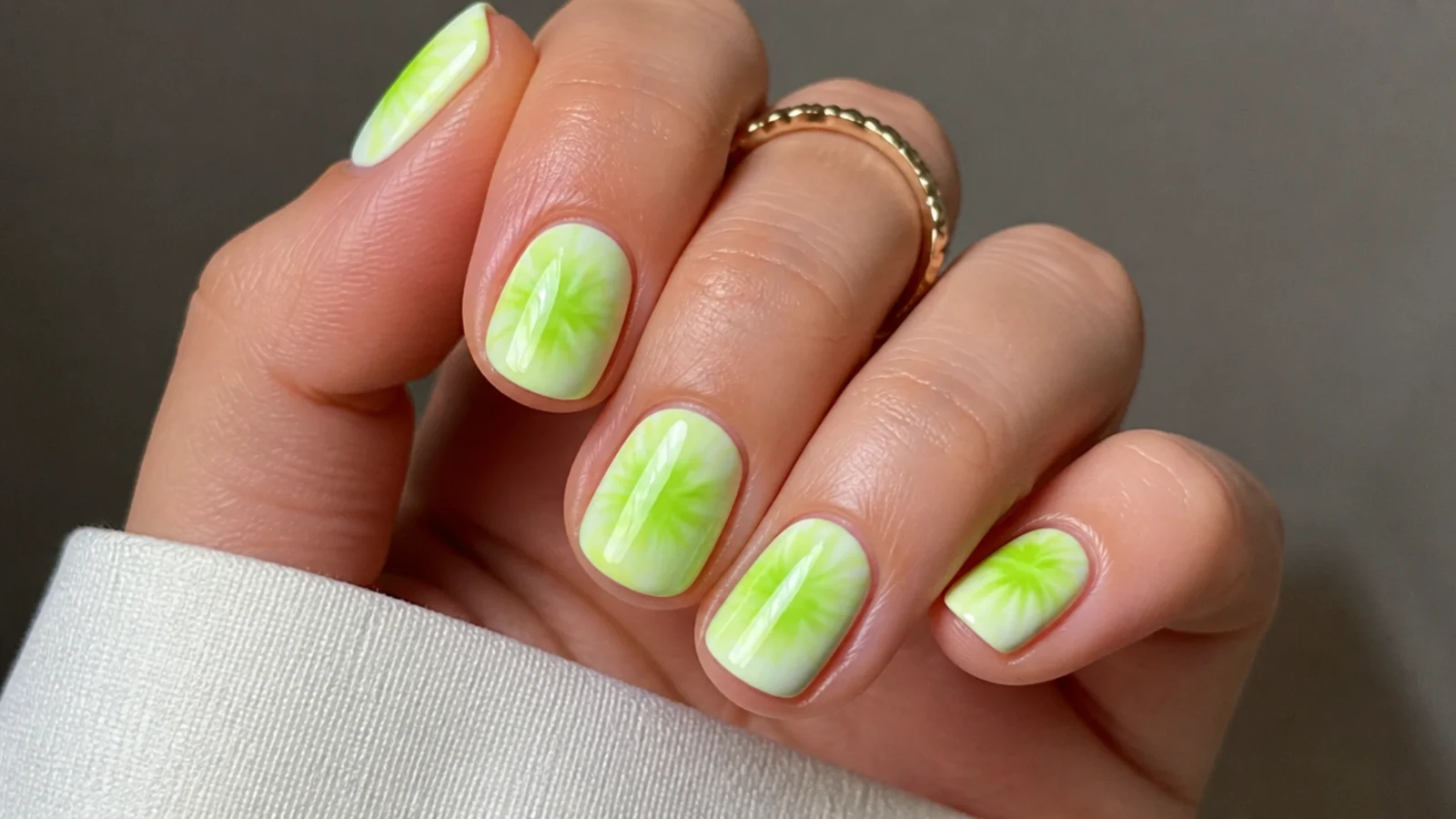 Bright lime green tie-dye diffusion over a white base on short nails