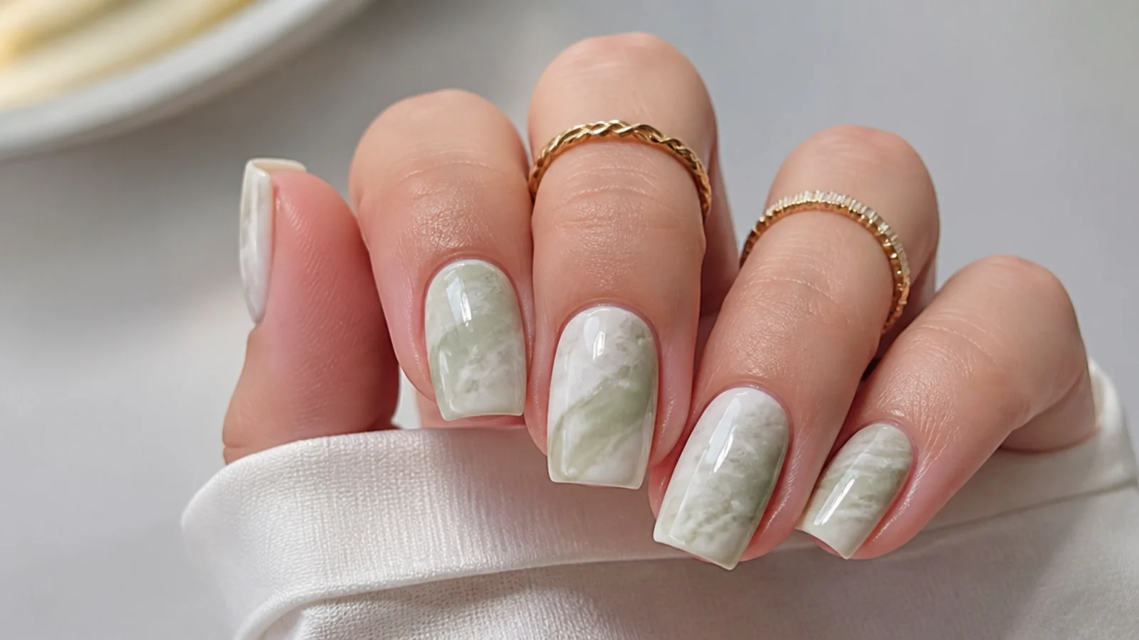 Soft green and white cloudy marble diffused over a base on square nails