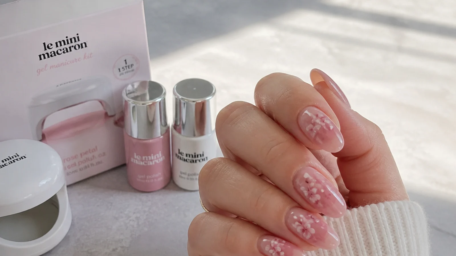 Pink blooming gel nails beside a small DIY gel kit