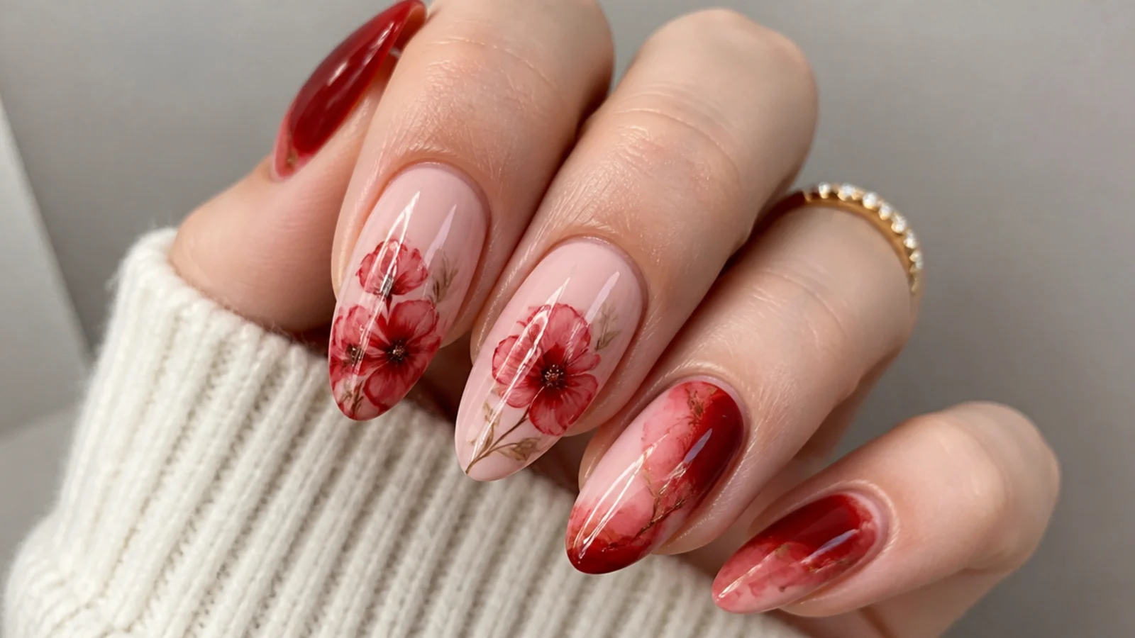 Bold red blooming gel nails with a soft watercolor rose spread across an almond shape