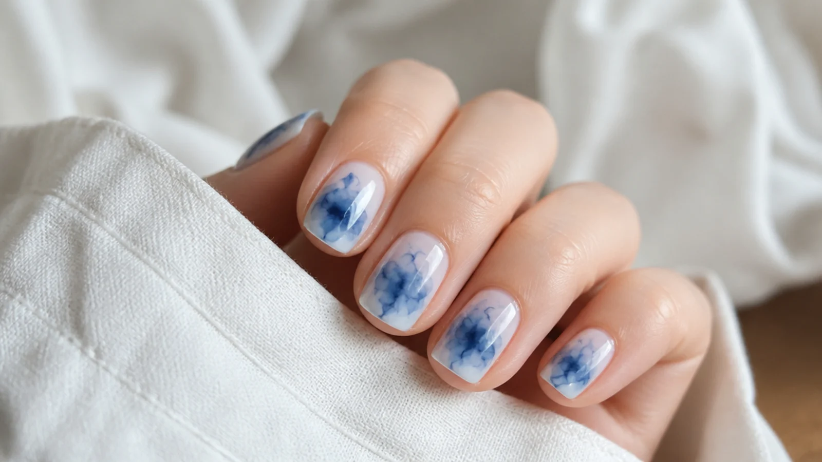 Short nails with an inky blue and white tie-dye bloom