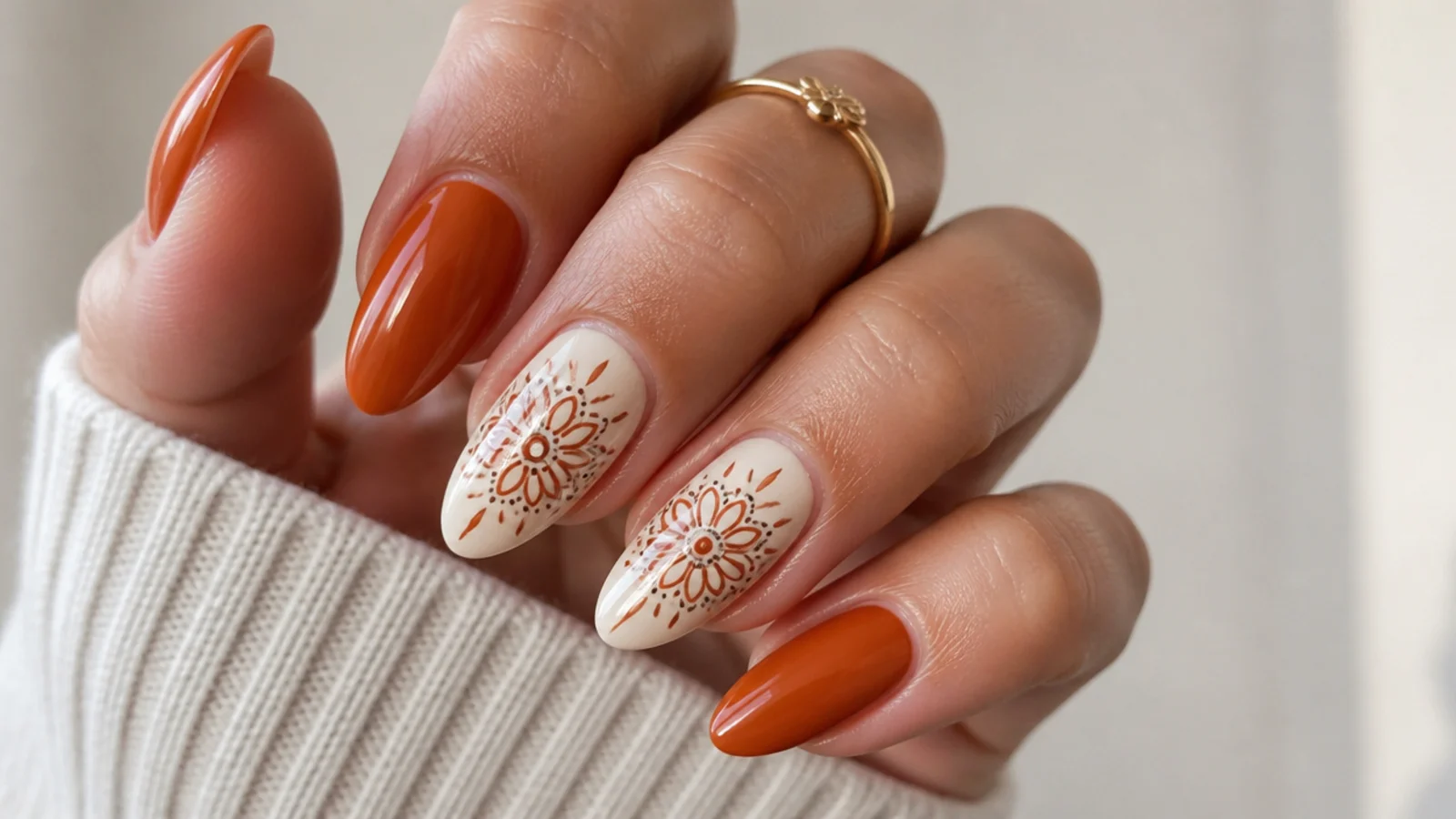 Burnt orange nails with a cream floral mandala on almond accent nails