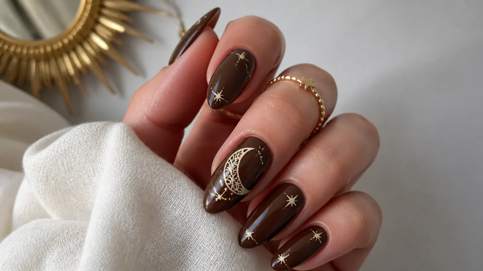 Deep brown nails with a cream crescent-moon mandala and tiny stars