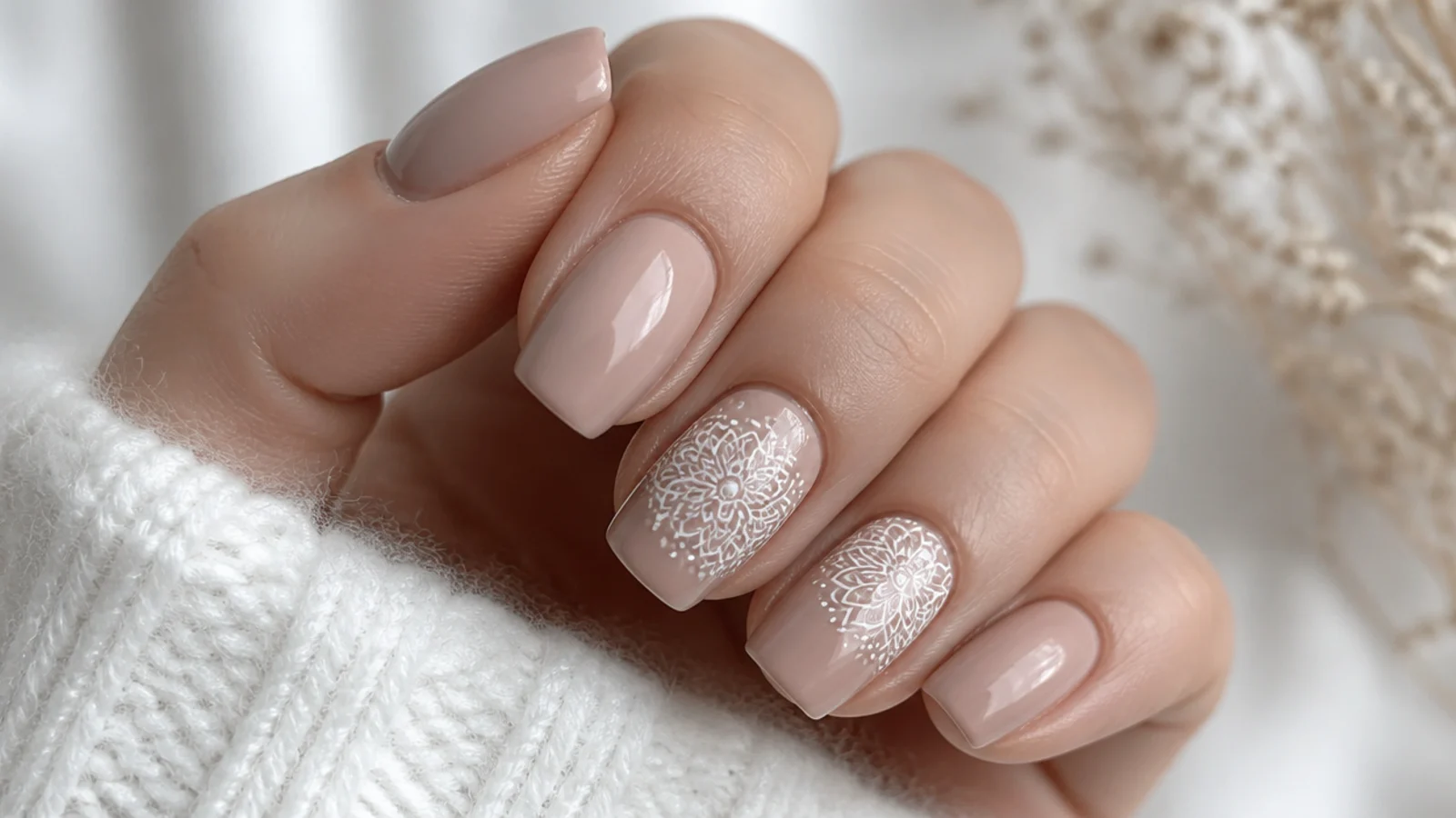 Nude nails with an intricate white lace-like mandala on accent nails
