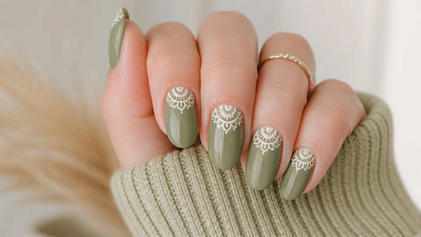 Sage green boho spring nails with a cream half-mandala at the cuticle on oval nails