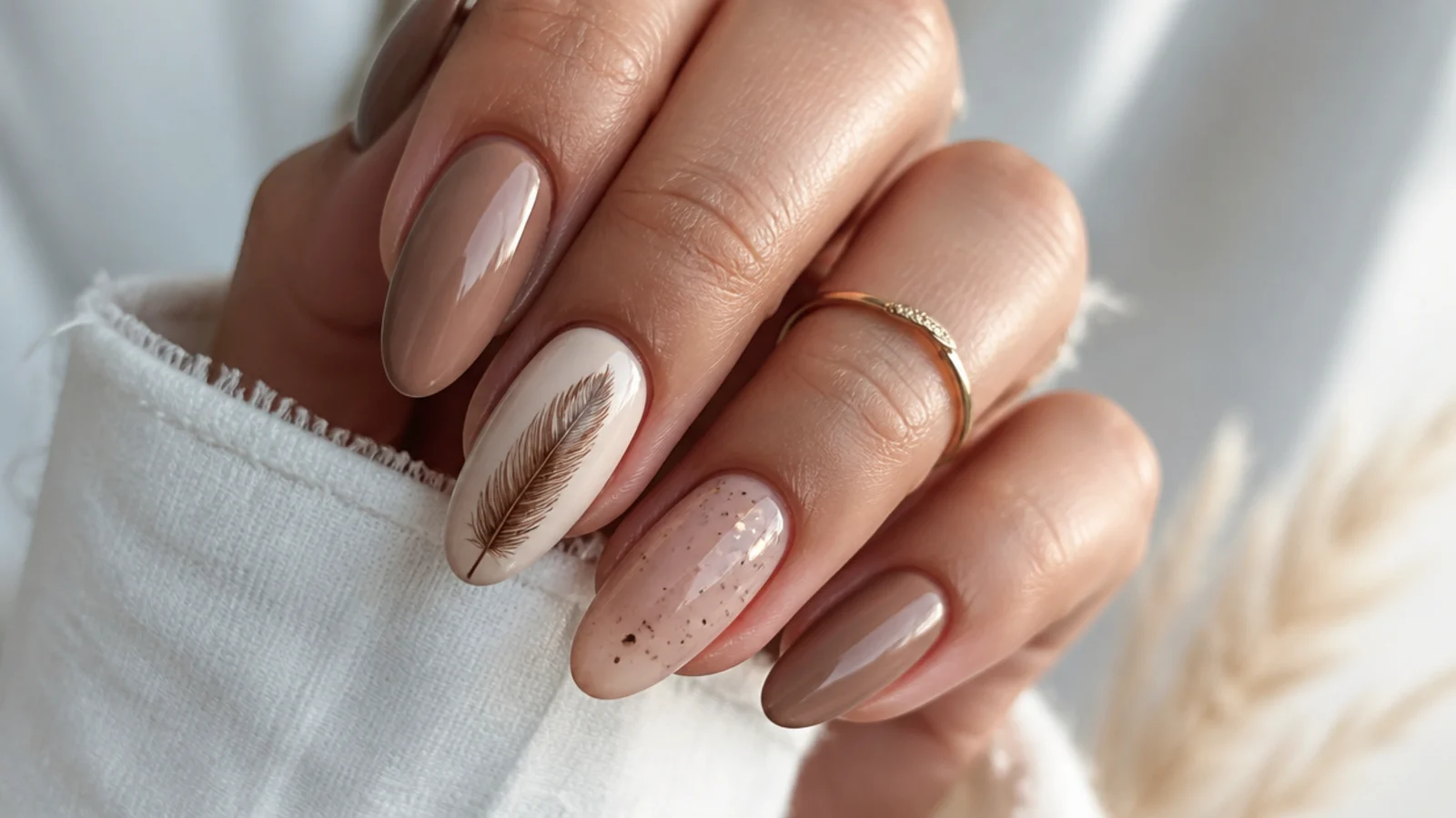 Tan boho spring nails with a fine brown feather on one accent nail