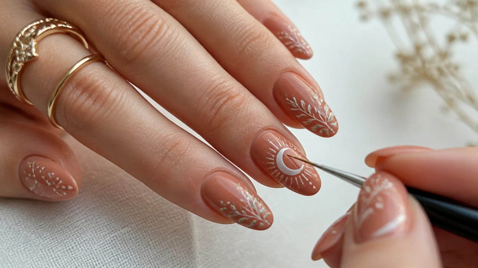 Boho spring nails being hand-painted with a fine liner over a terracotta base