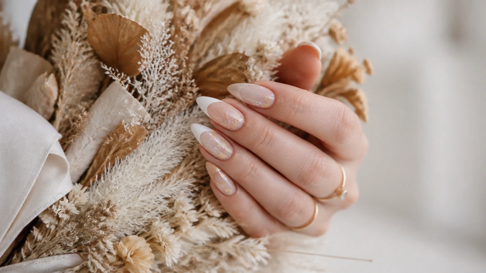 Boho wedding nails on a bride's hand holding an earthy dried-floral bouquet