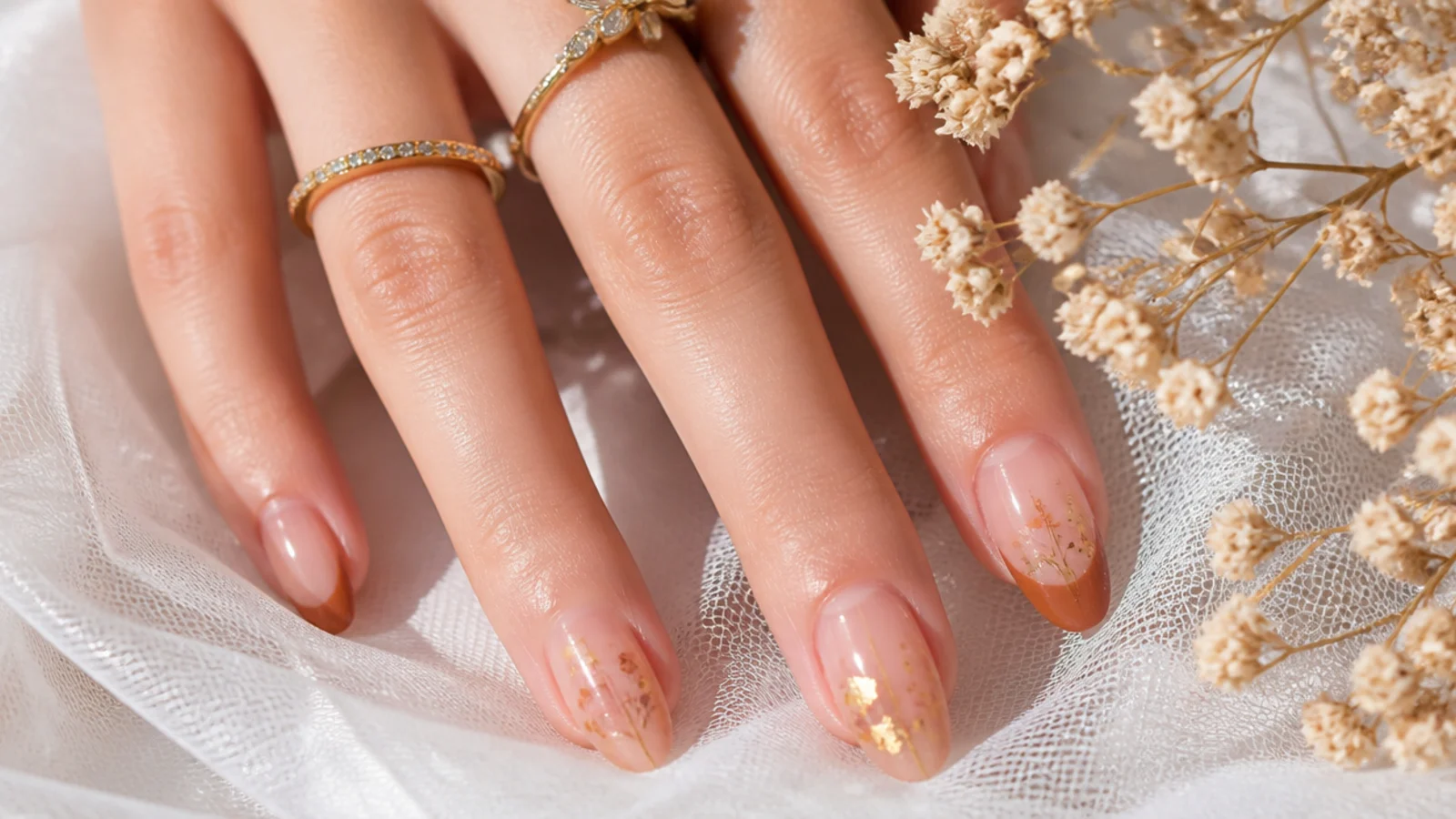 Earthy boho nails styled with dried flowers and gold jewelry for a wedding