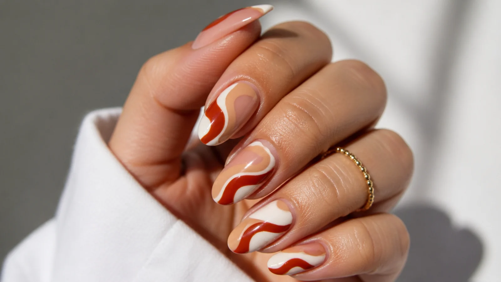 Abstract rust and cream swirl boho nails in a 70s pattern