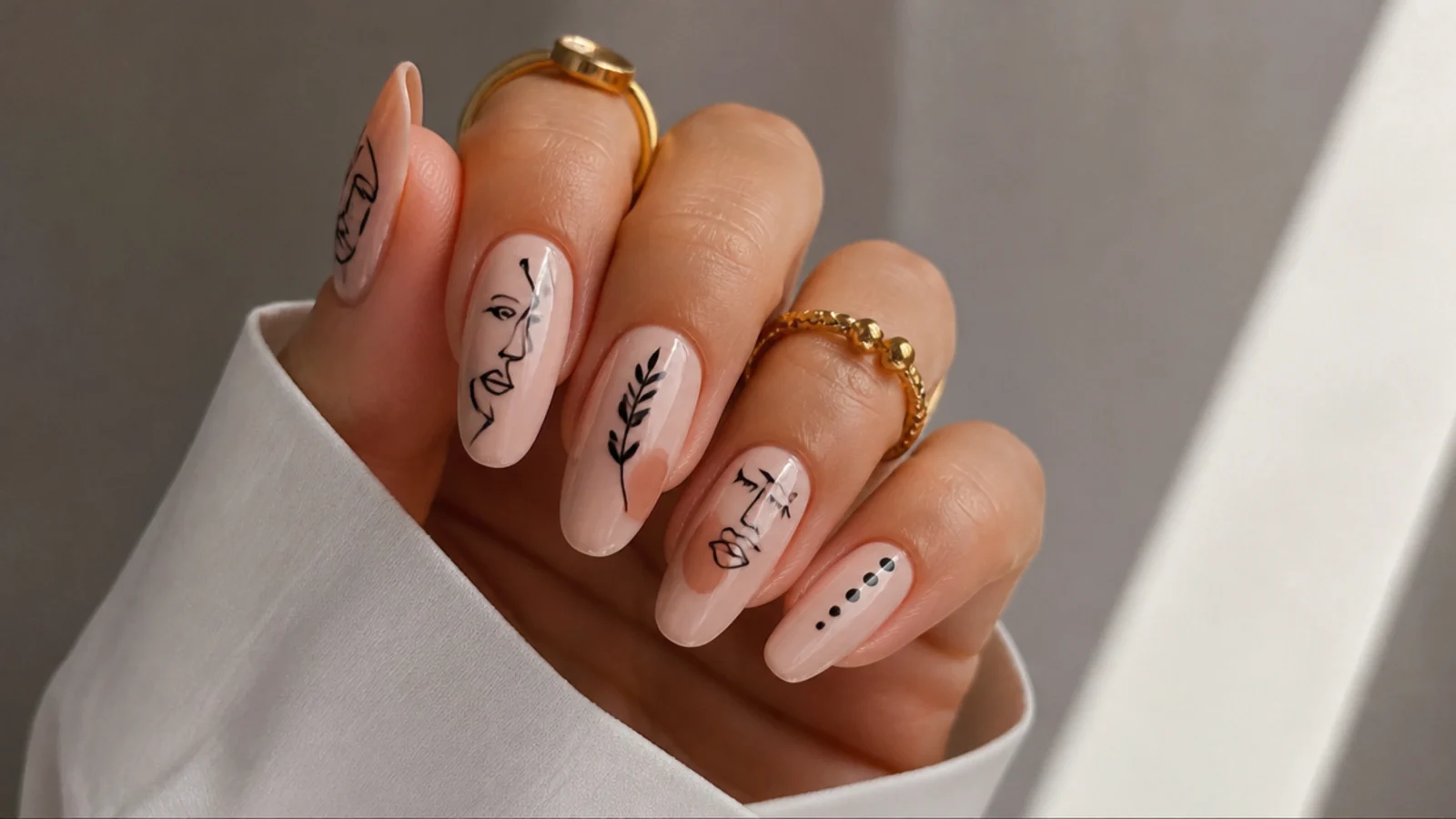 Minimal black line-art faces and shapes on nude boho nails