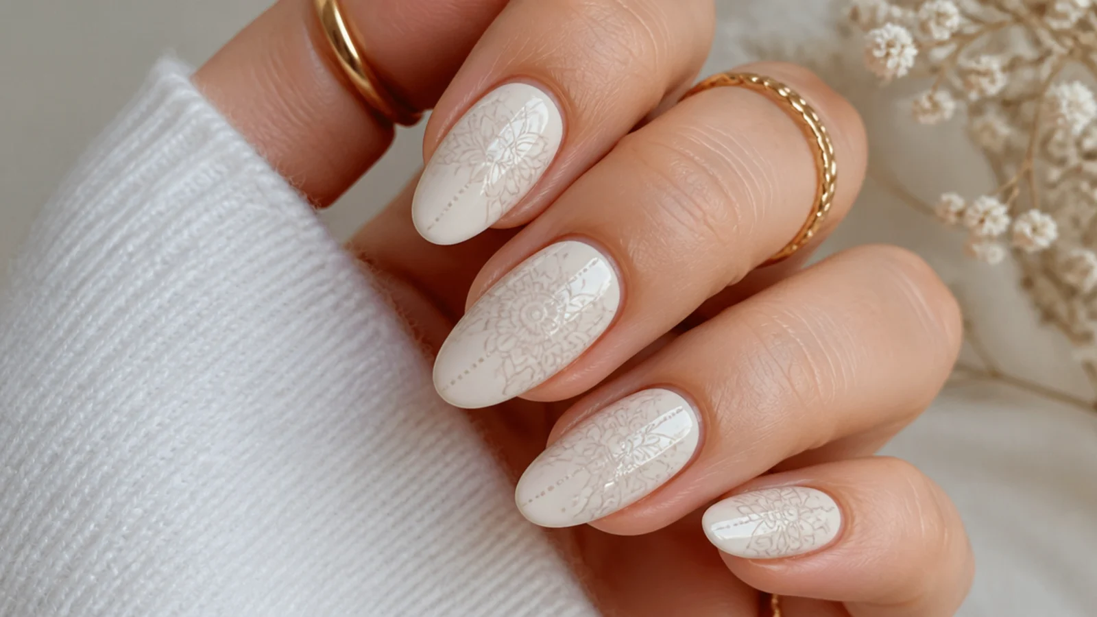 A faint pencil-light sketch of a floral and mandala layout planned on cream nails