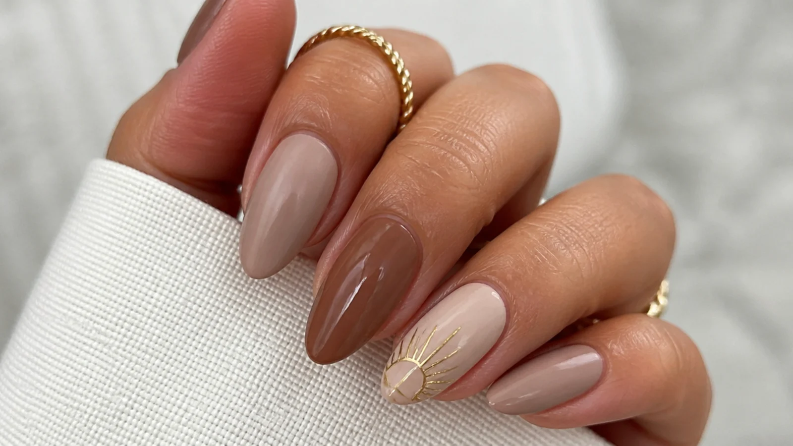 Tan boho nails with a small muted gold rising sun on one accent nail