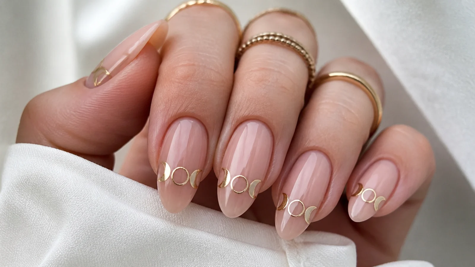 Nude boho nails with a fine gold moon-phase line across the tips