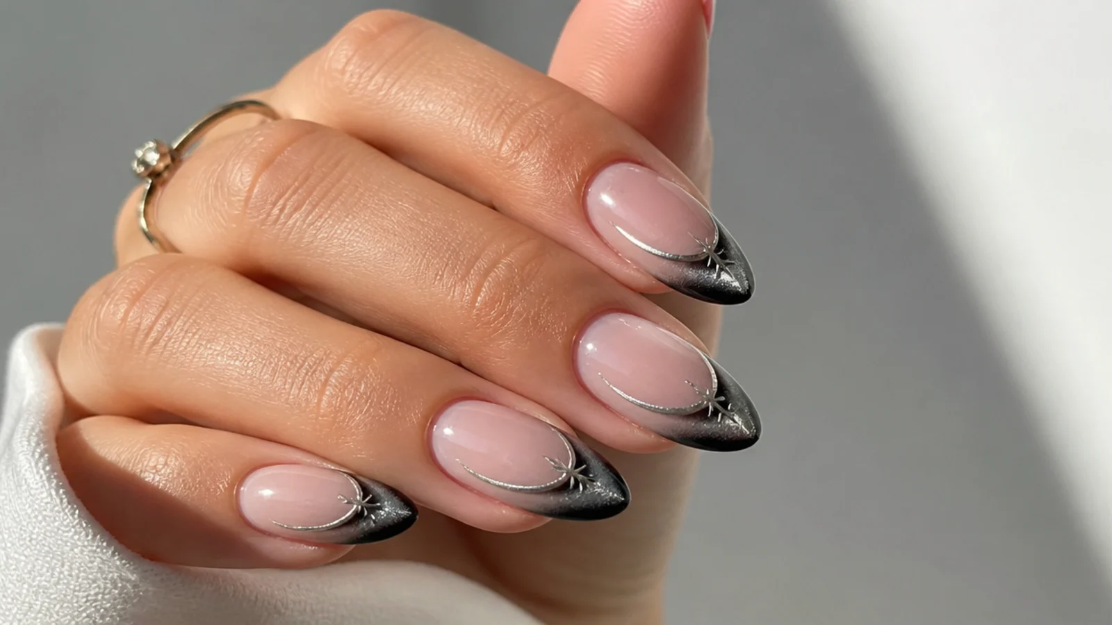 Almond nails with a black magnetic cat eye french tip and silver shine