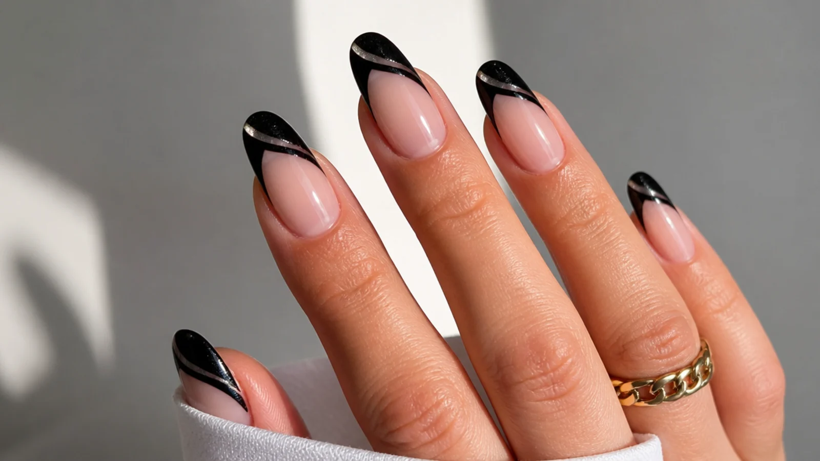 Black french tip nails with a diagonal cat eye light stripe across each tip