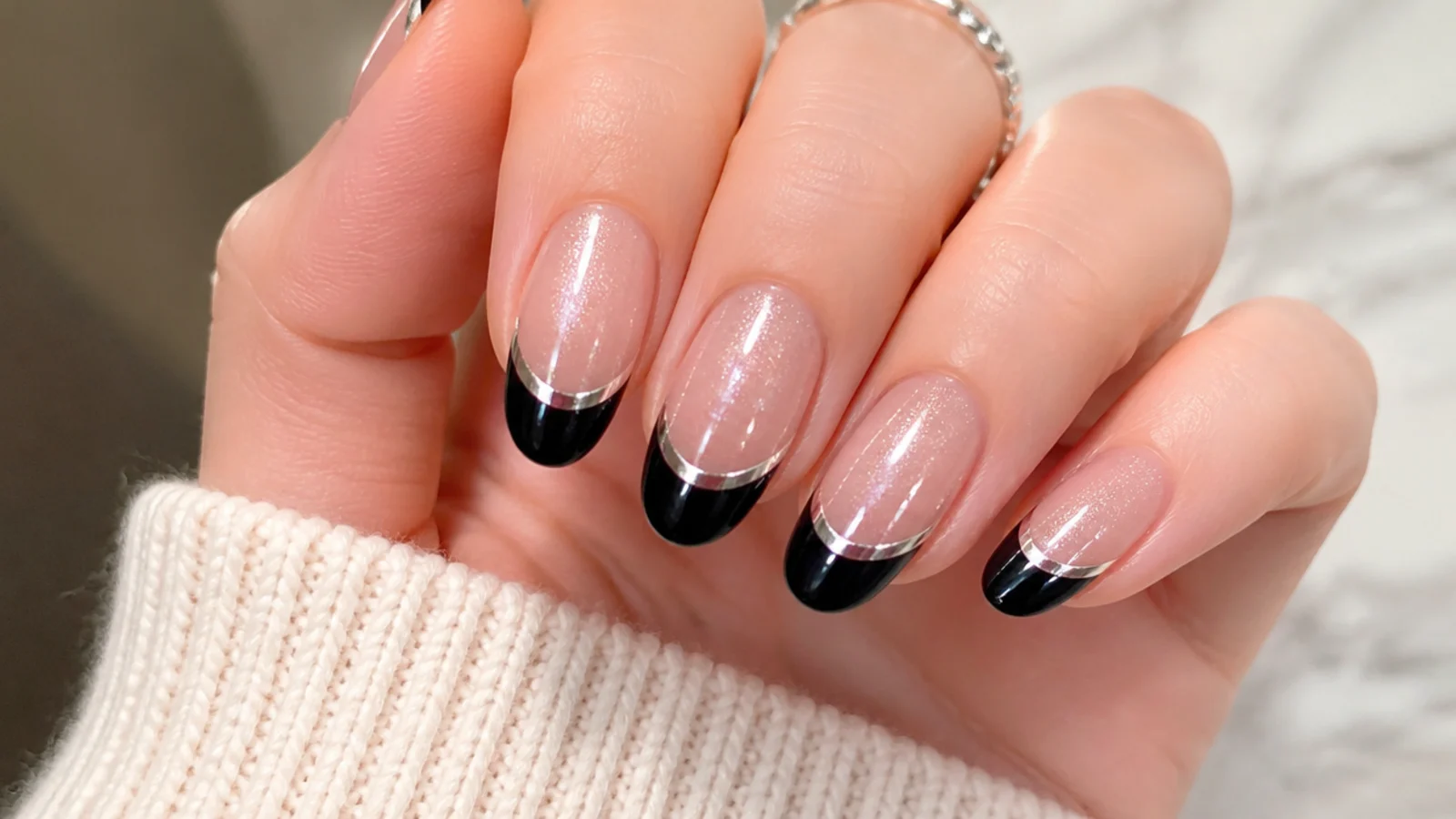 Black french tip nails with a thin silver line under the cat eye stripe