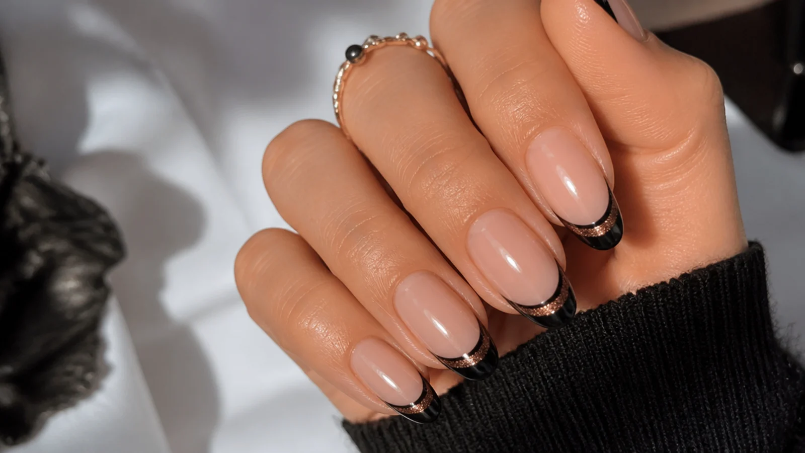 Black french tip nails with a warm rose gold cat eye stripe