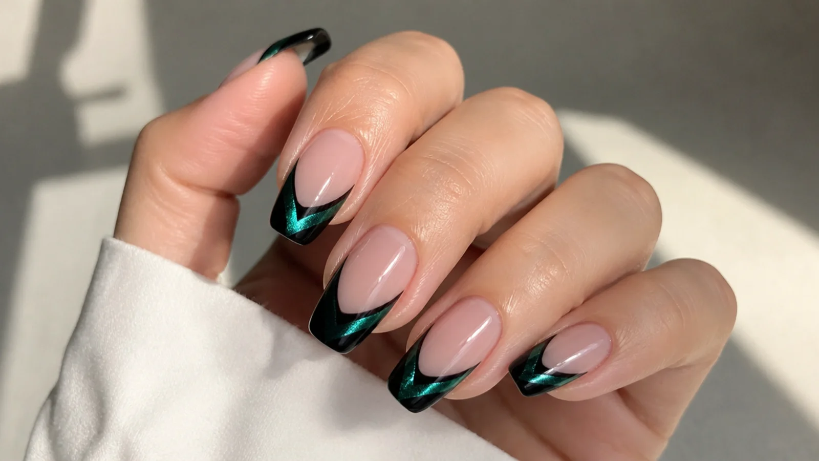 Black french tip nails with a green emerald cat eye stripe