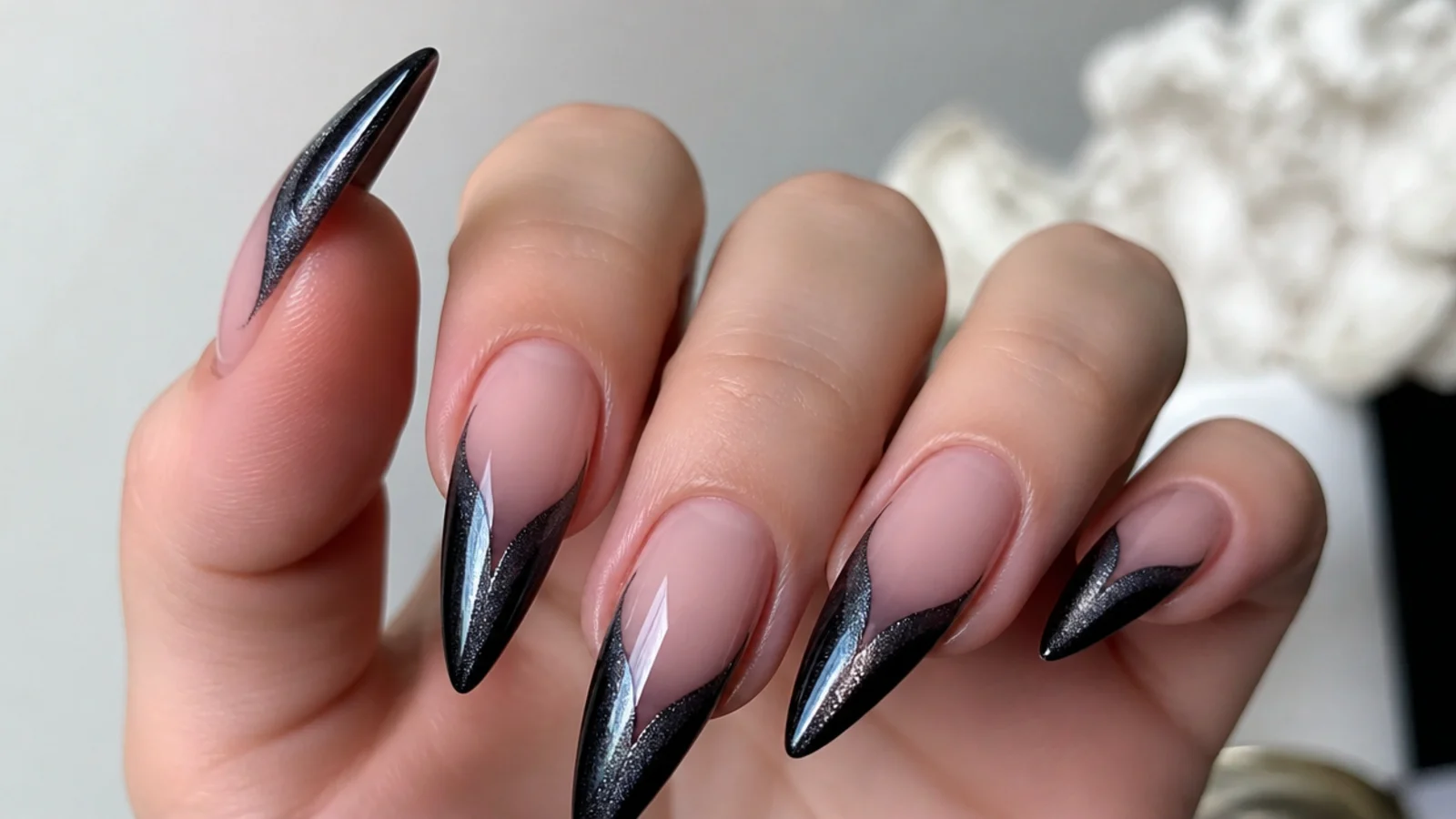 Long stiletto black cat eye french tip nails with a diagonal light stripe