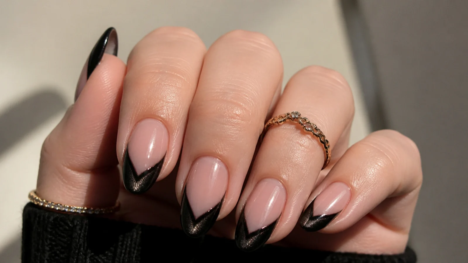 Black V-shaped french tip nails with a cat eye light stripe following the point