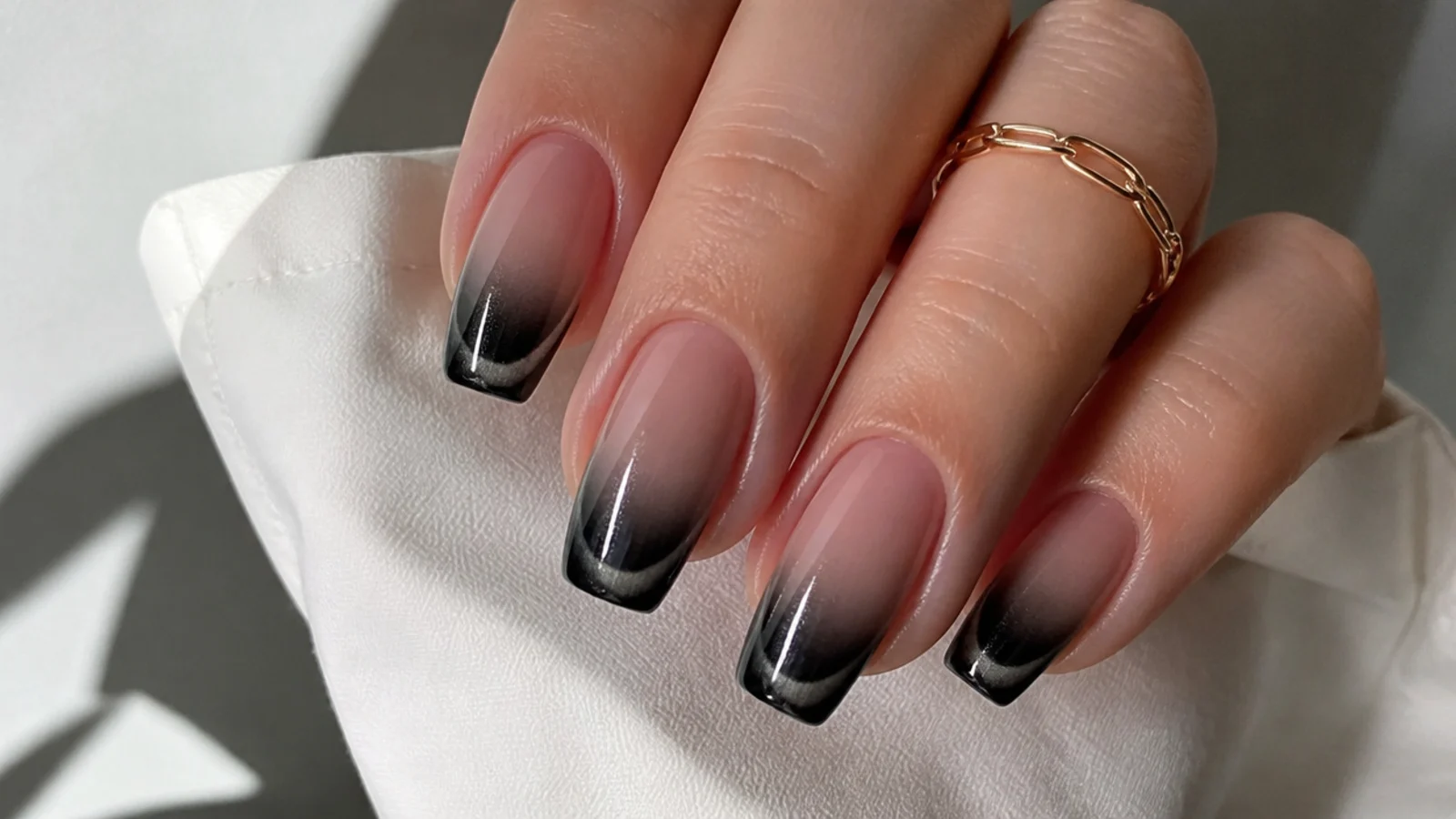 Black to nude ombre french nails with a cat eye light stripe at the tip