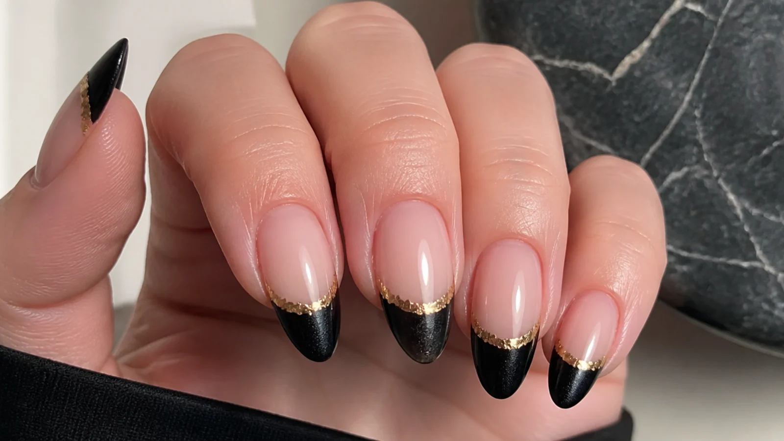 Black cat eye french tip nails with thin gold foil accents at the smile line