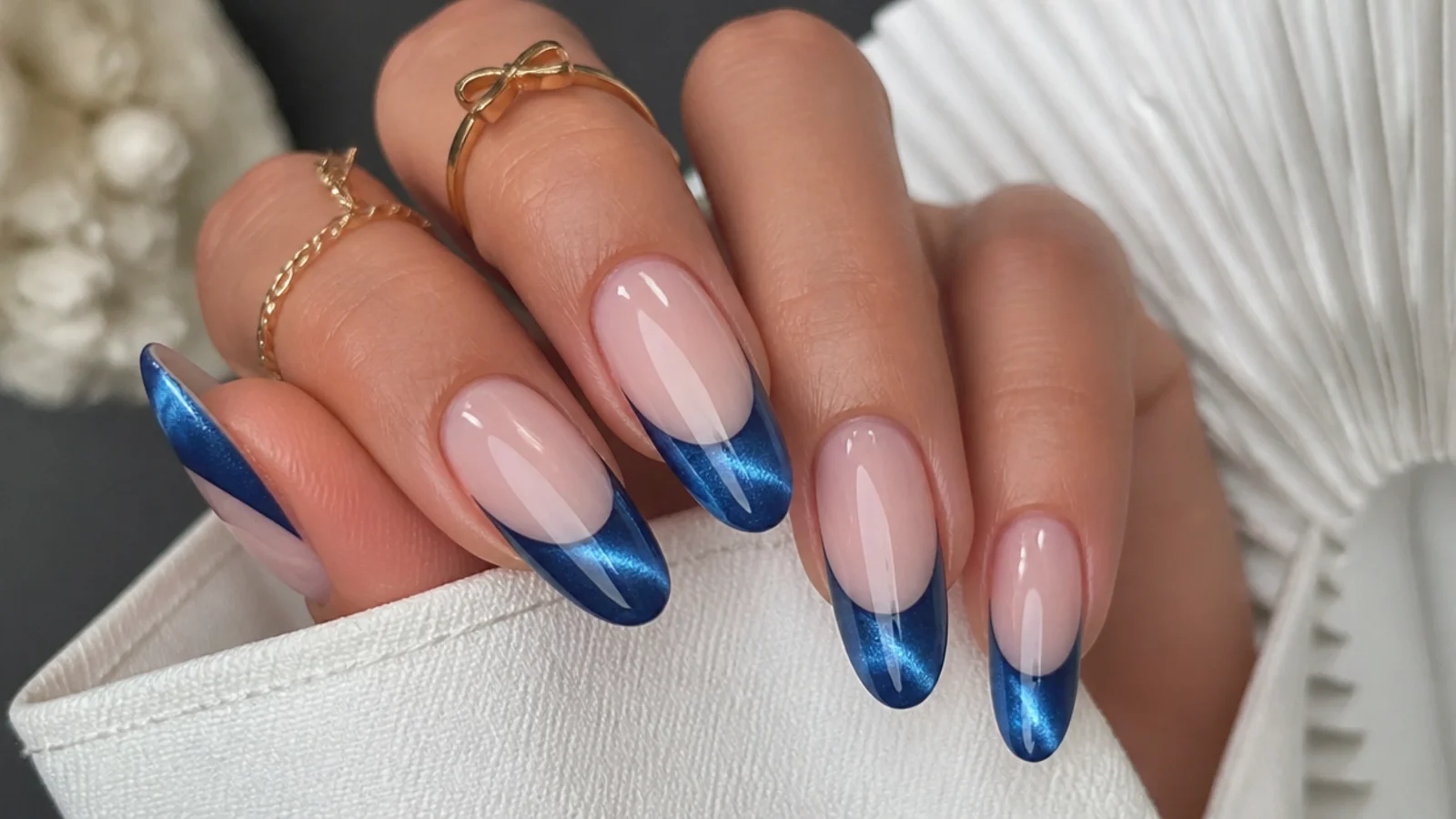 Royal blue cat eye french tips on long almond nails with a curved light stripe