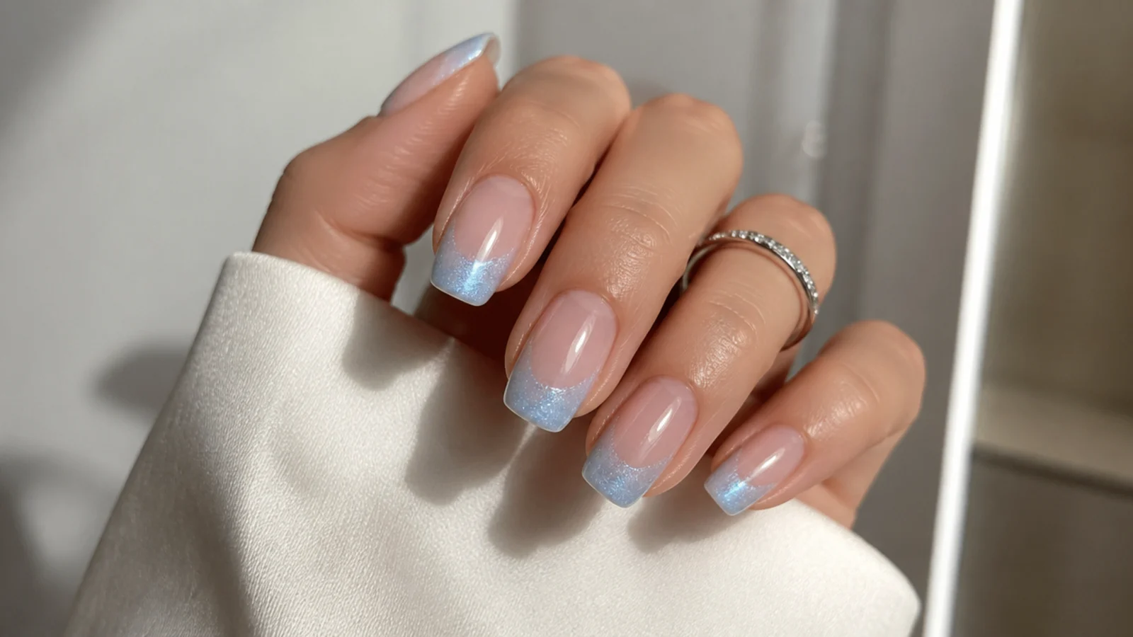 Baby blue cat eye french tips fading into a nude base with a soft light stripe