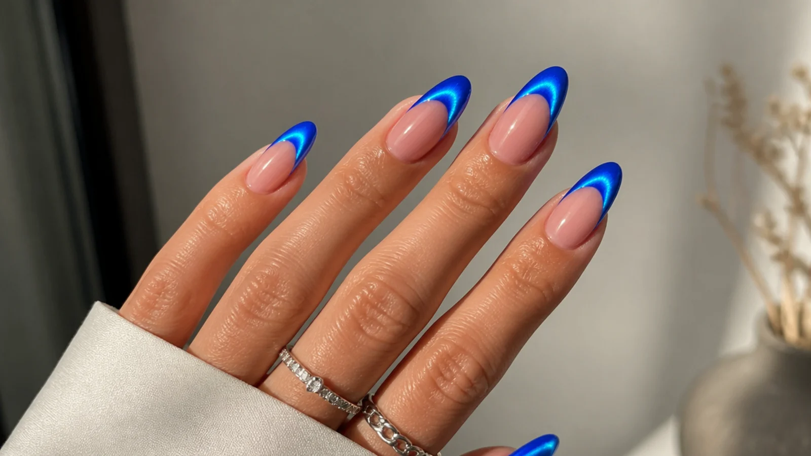 Bright electric blue cat eye french tip nails with a vivid glowing stripe