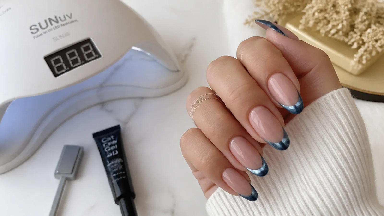 Blue magnetic gel, a magnet and a lamp laid out for a DIY cat eye french tip